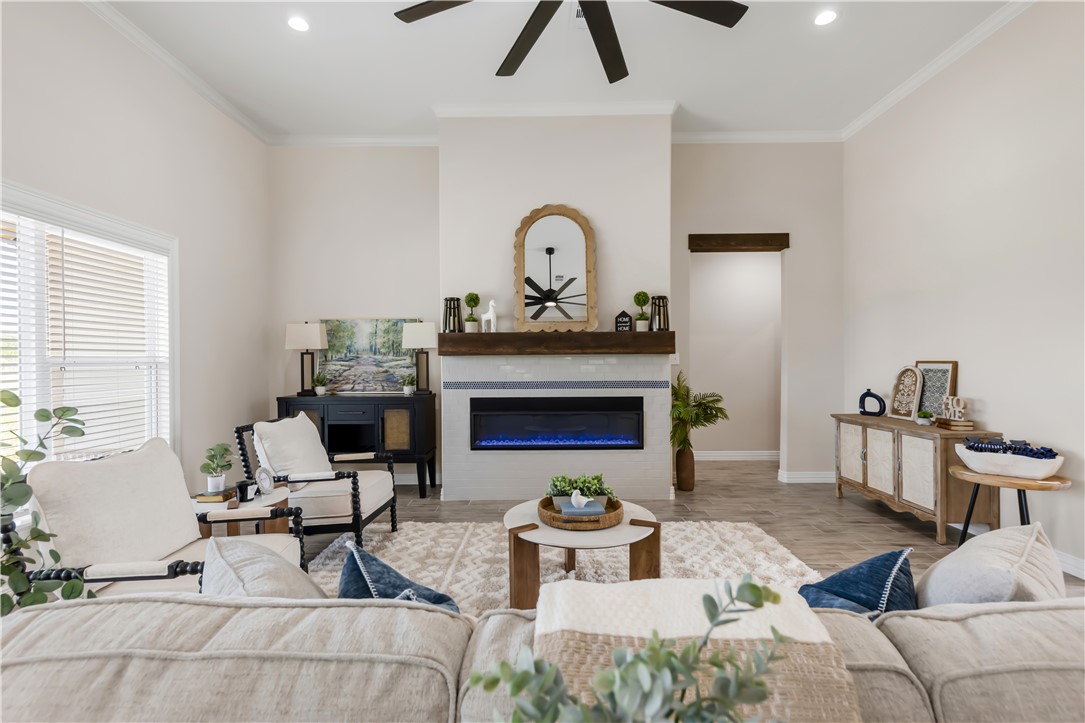 3310 Hunters Crossing Bryan, TX 77808 - Photo 11 of 34 Living area featuring ornamental molding, a glass covered fireplace, recessed lighting, wood finished floors, and ceiling fan