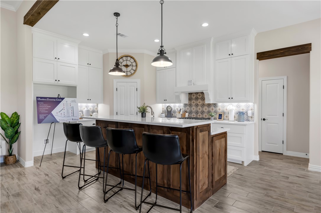 3310 Hunters Crossing Bryan, TX 77808 - Photo 13 of 34 Kitchen with tasteful backsplash, white cabinetry, an island with sink, a kitchen bar, and light wood-style floors