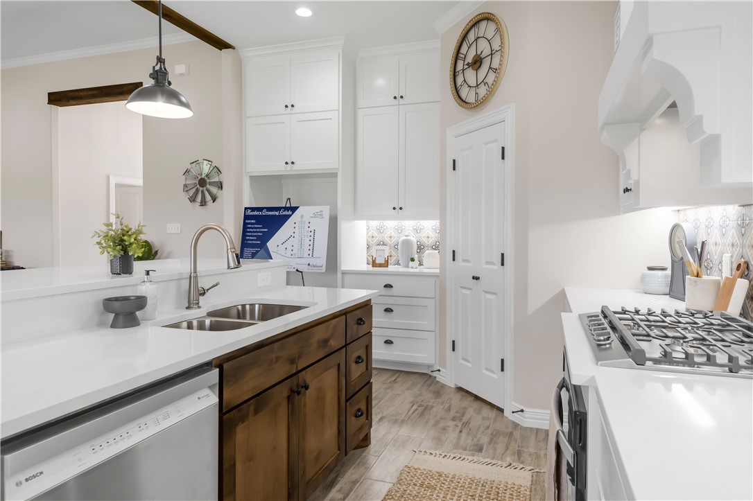 3310 Hunters Crossing Bryan, TX 77808 - Photo 15 of 34 Kitchen with stainless steel appliances, white cabinetry, decorative light fixtures, light wood-type flooring, and ornamental molding