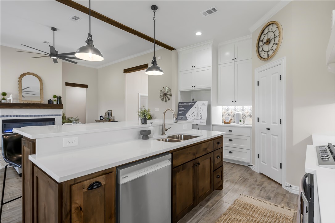3310 Hunters Crossing Bryan, TX 77808 - Photo 16 of 34 Kitchen featuring crown molding, stainless steel appliances, white cabinets, light wood finished floors, and decorative light fixtures