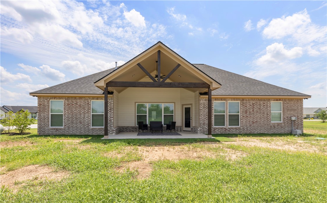 3310 Hunters Crossing Bryan, TX 77808 - Photo 31 of 34 Back of house featuring roof with shingles, a patio, brick siding, and a lawn