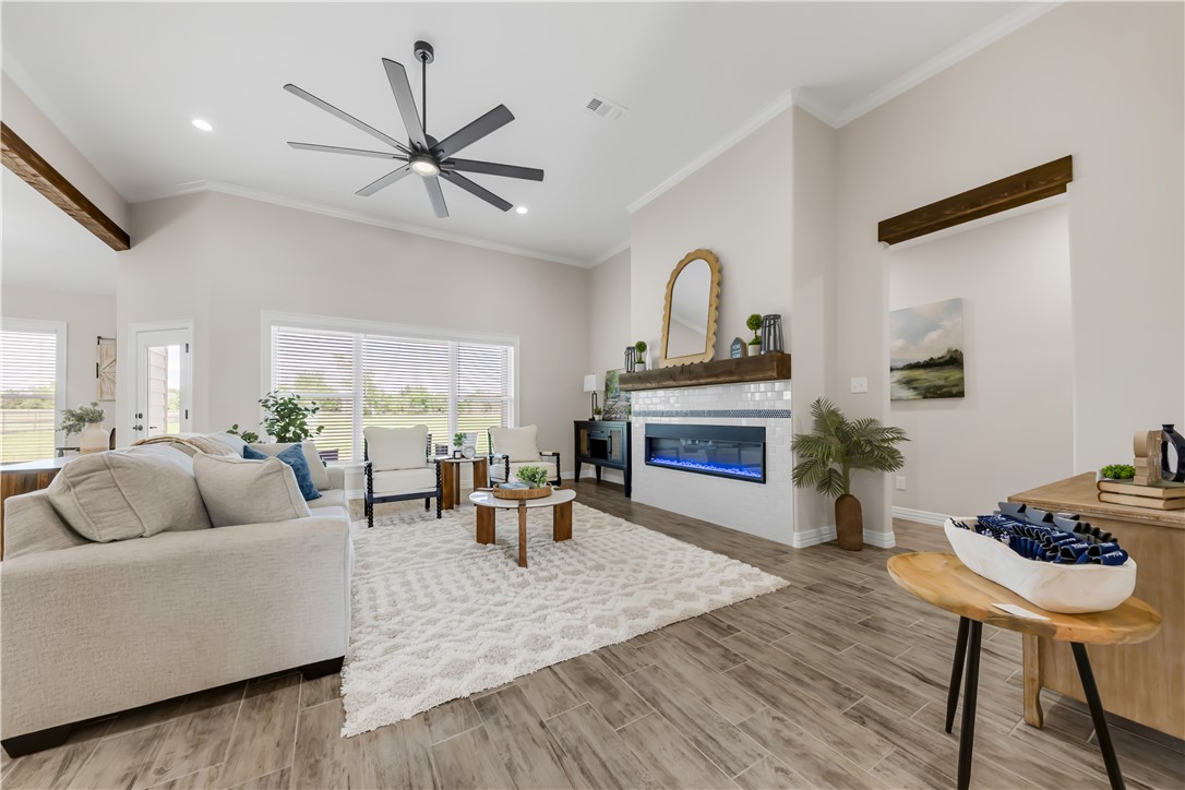 3310 Hunters Crossing Bryan, TX 77808 - Photo 7 of 34 Living room featuring wood finish floors, a glass covered fireplace, crown molding, ceiling fan, and recessed lighting