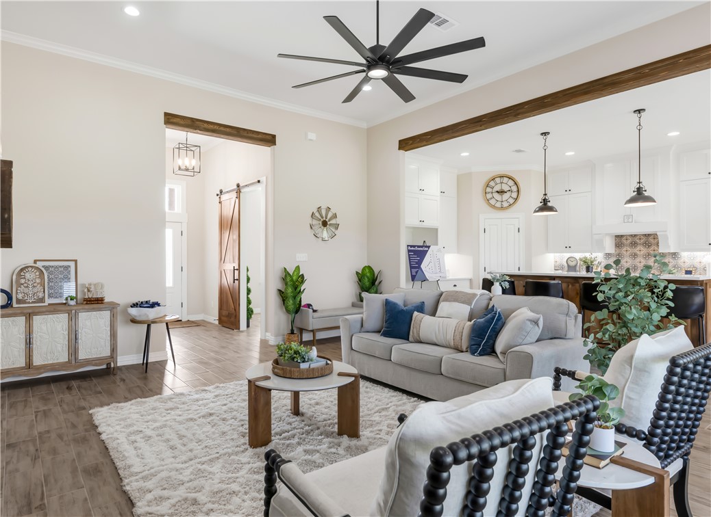 3310 Hunters Crossing Bryan, TX 77808 - Photo 9 of 34 Living room featuring a barn door, wood finish floors, recessed lighting, ornamental molding, and ceiling fan