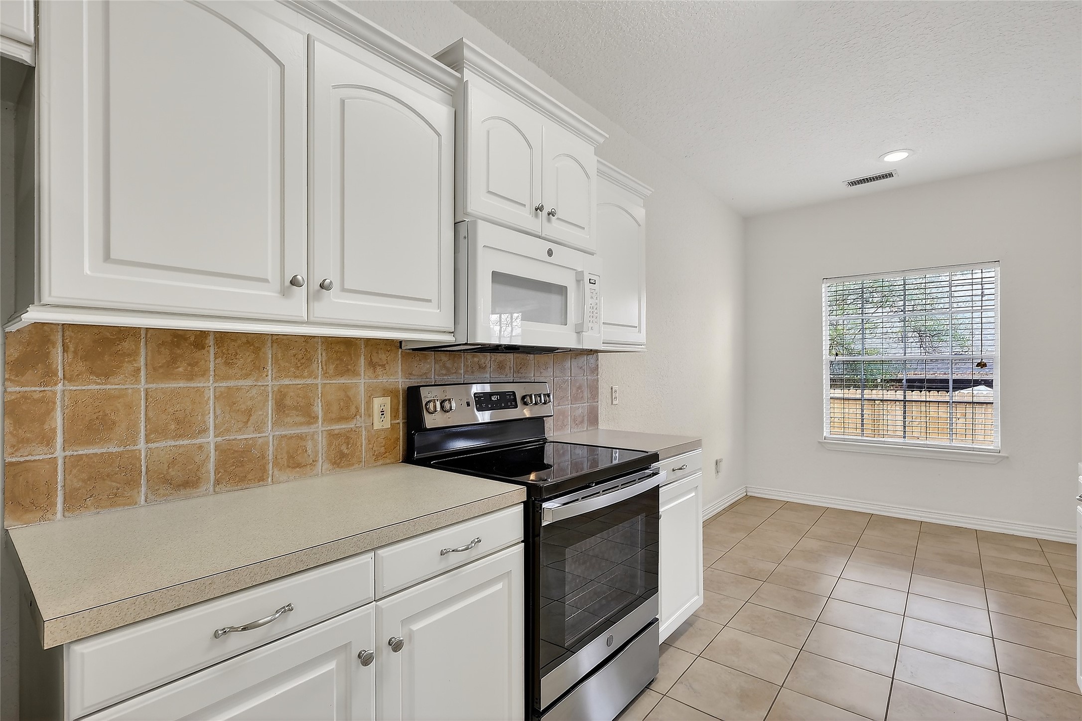 89 Dawns Edge Conroe, TX 77356 - Photo 9 of 46 Well-appointed kitchen showcasing ample counter space, tile accents, built-in microwave, and adjoining breakfast area.