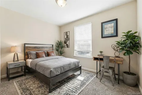 a bedroom with a bed table chair and potted plant