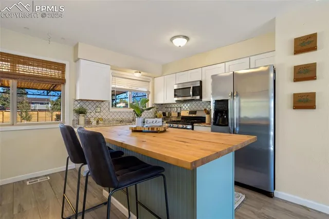a kitchen with stainless steel appliances a table chairs and refrigerator