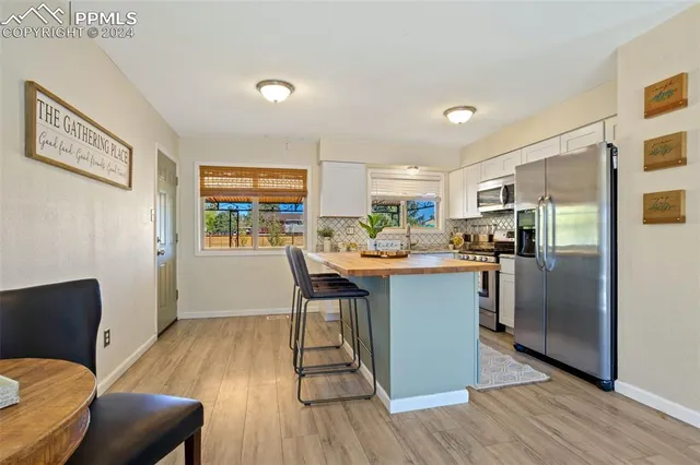 a kitchen with stainless steel appliances a dining table chairs refrigerator and sink