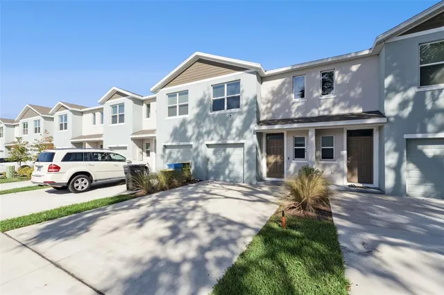 a view of a white house with large windows and lawn chairs