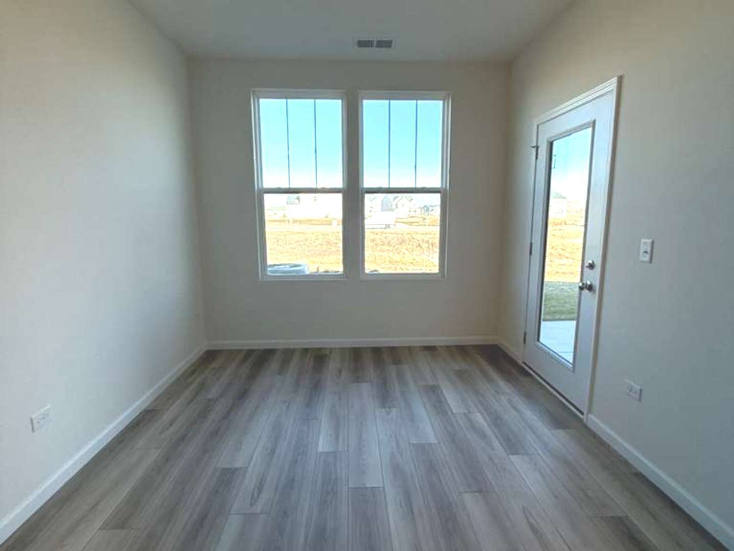 672 Switchgrass Way, Unit 58005 Bolingbrook, IL 60490 - Photo 11 of 19 an empty room with wooden floor and windows
