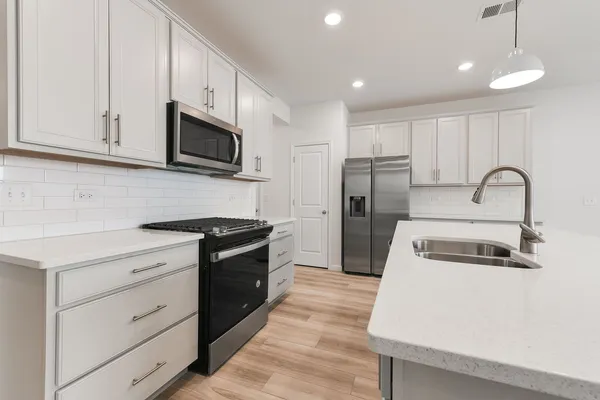 a kitchen with white cabinets stainless steel appliances and a sink