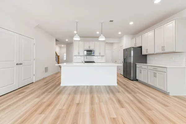 a large white kitchen with wooden floors stainless steel appliances and white cabinets