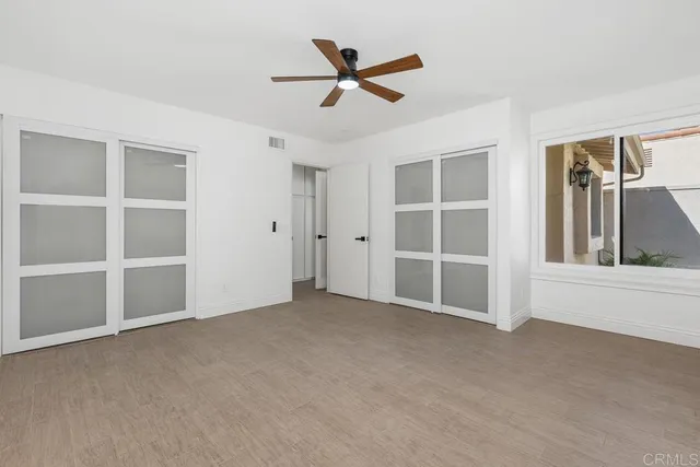 an empty room with closet and ceiling fan