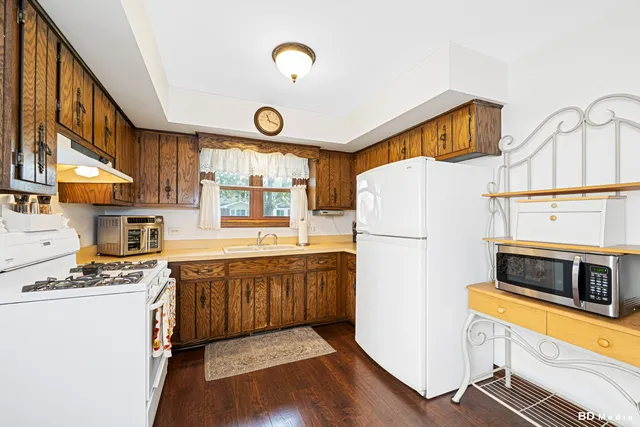 a kitchen with stainless steel appliances a refrigerator a stove a sink and a refrigerator with wooden floor