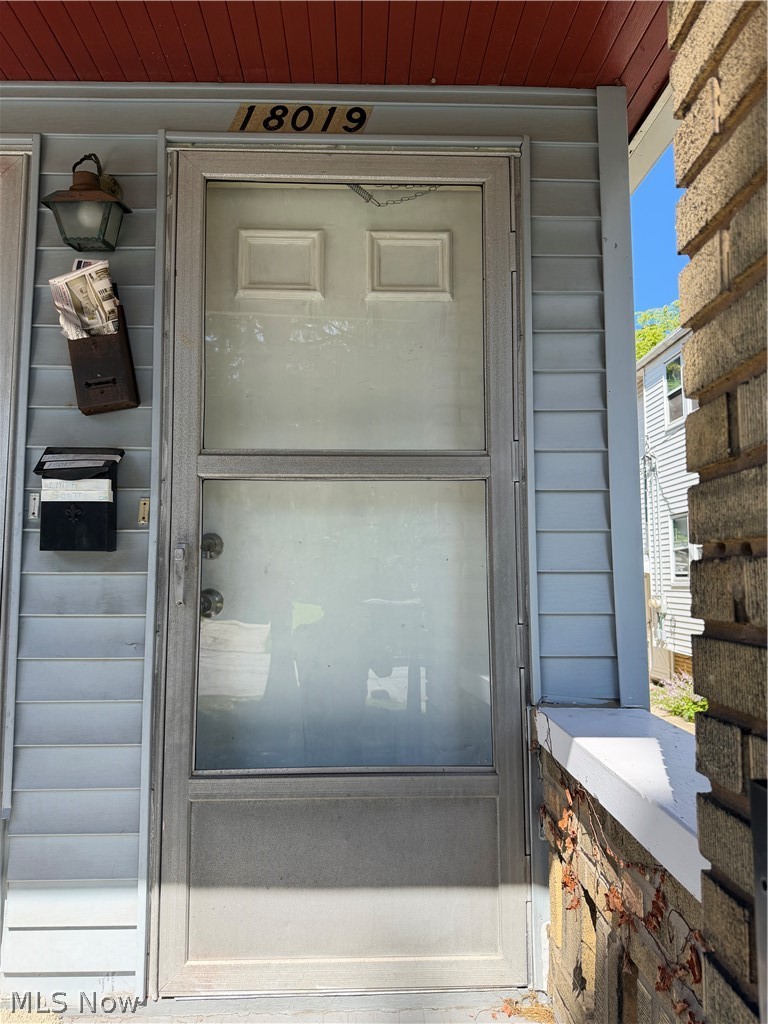 18017 Olympia Road Cleveland, OH 44112 - Photo 11 of 34 Front entry featuring a storm door, exterior wall light, and house number