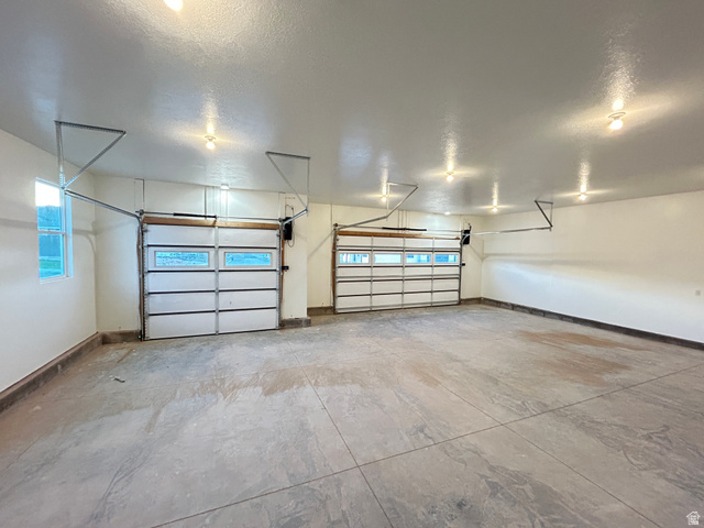 6 South 450th West Gunnison, UT 84634 - Photo 44 of 45 Expansive garage featuring two overhead doors with window inserts, concrete flooring, and multiple ceiling-mounted light fixtures