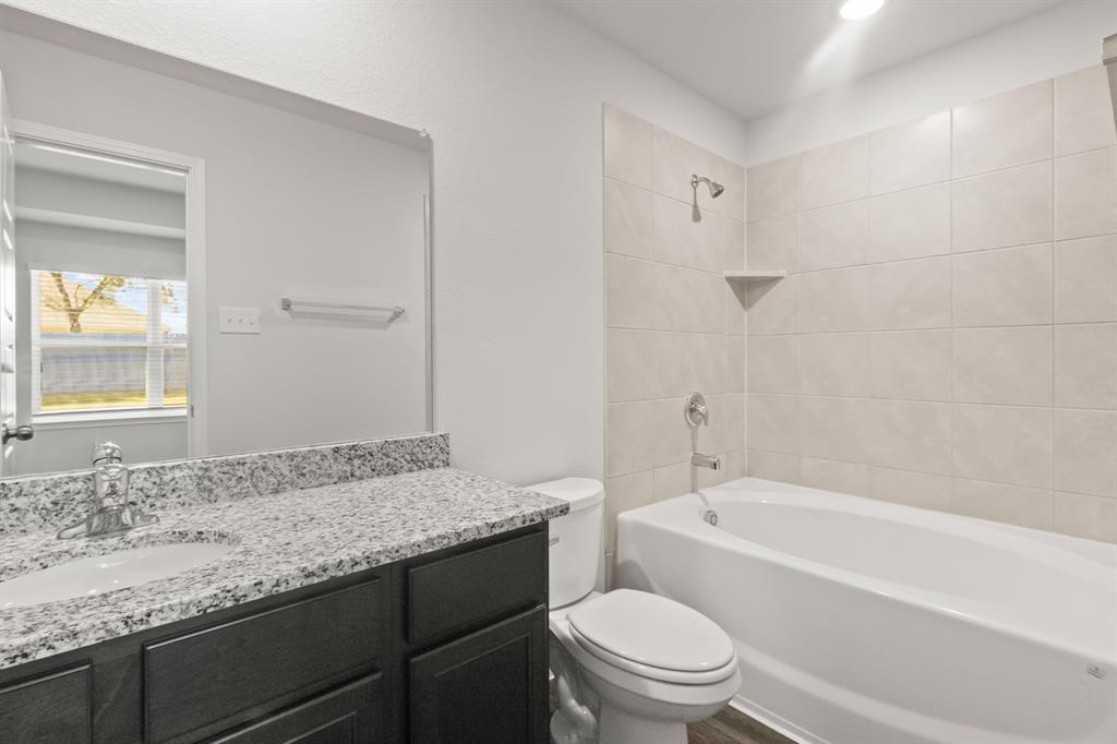 1505 Romans Road Ennis, TX 75119 - Photo 7 of 13 a bathroom with a granite countertop sink a toilet and bathtub