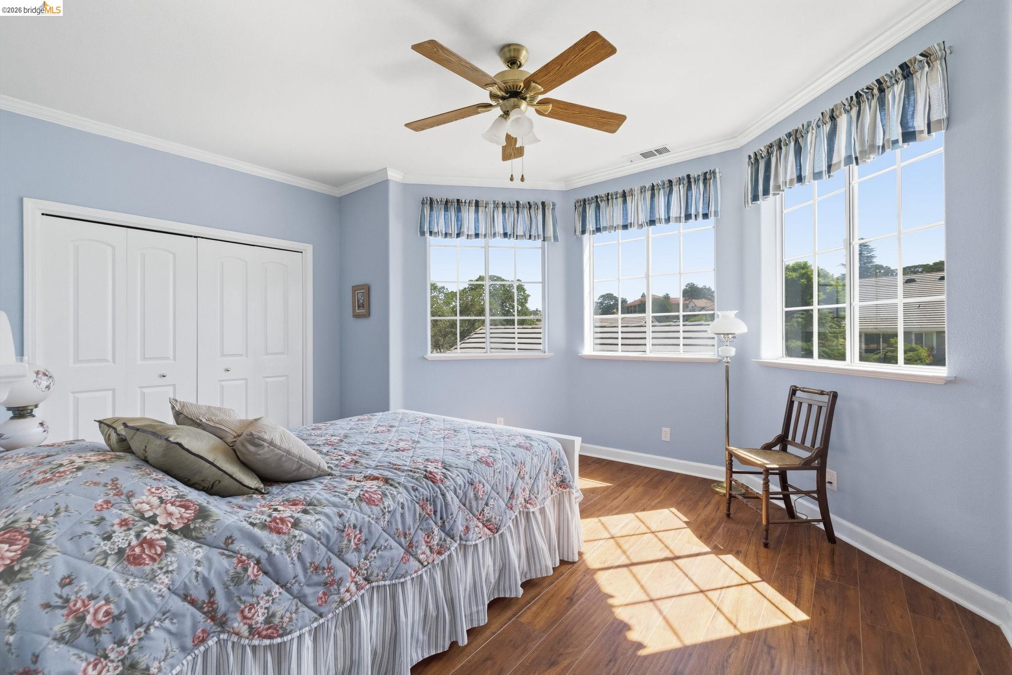 6242 Bluff View Road Copperopolis, CA 95228 - Photo 41 of 59 Spacious room featuring multiple large windows, wood-finish flooring, a ceiling fan with integrated lighting, crown molding, and white bi-fold closet doors