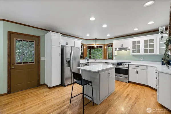 a kitchen with stainless steel appliances granite countertop a refrigerator a sink dishwasher a stove with wooden cabinets and wooden floor