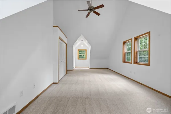 an empty room with windows and ceiling fan
