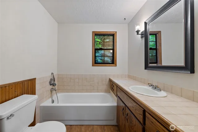 a bathroom with a granite countertop sink mirror toilet and bathtub