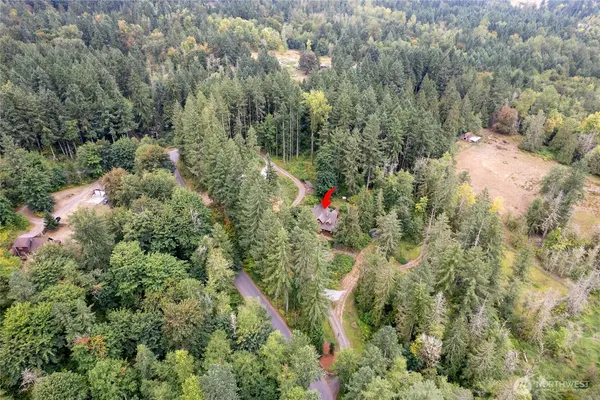 an aerial view of residential house with outdoor space and trees all around