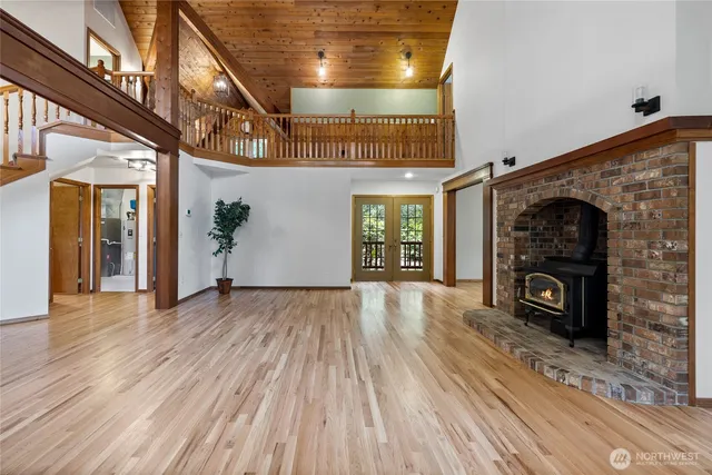 a view of an empty room with wooden floor fireplace and a window