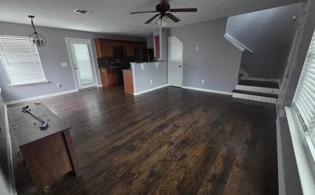 a view of a big room with wooden floor and windows