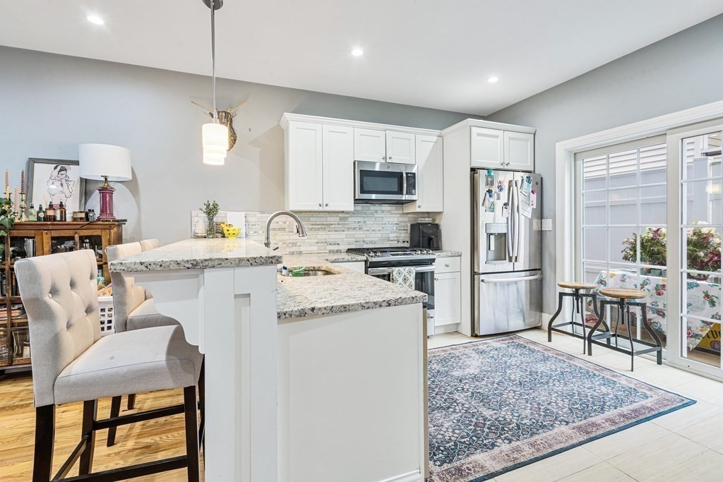 8 Loring Place, Unit 8 Boston, MA 02136 - Photo 8 of 23 a kitchen with stainless steel appliances granite countertop a refrigerator a stove a sink a dining table and chairs with wooden floor