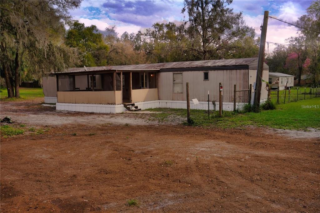 a view of a house with backyard and trees in the background