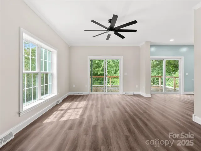 a view of a livingroom with wooden floor a ceiling fan and windows