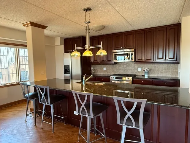 a kitchen with stainless steel appliances granite countertop a stove top oven a dining table and chairs with wooden floor