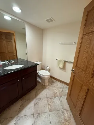 a spacious bathroom with a granite countertop sink toilet and mirror