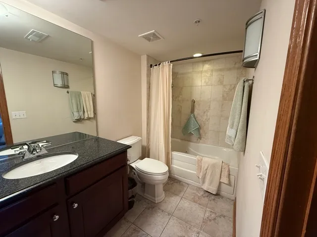 a bathroom with a granite countertop sink toilet and shower