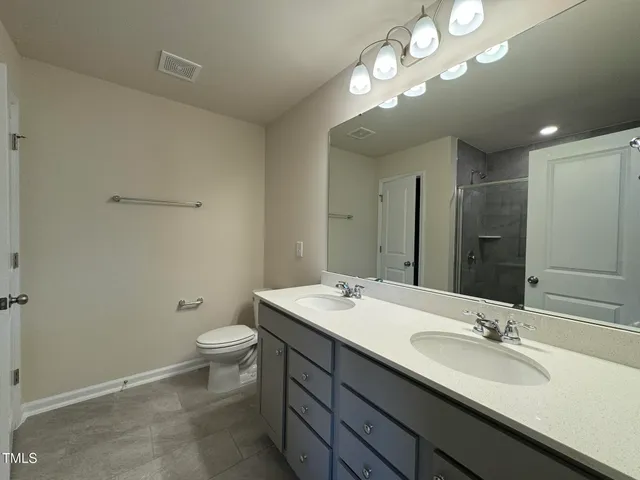 a bathroom with a double vanity sink toilet and a mirror