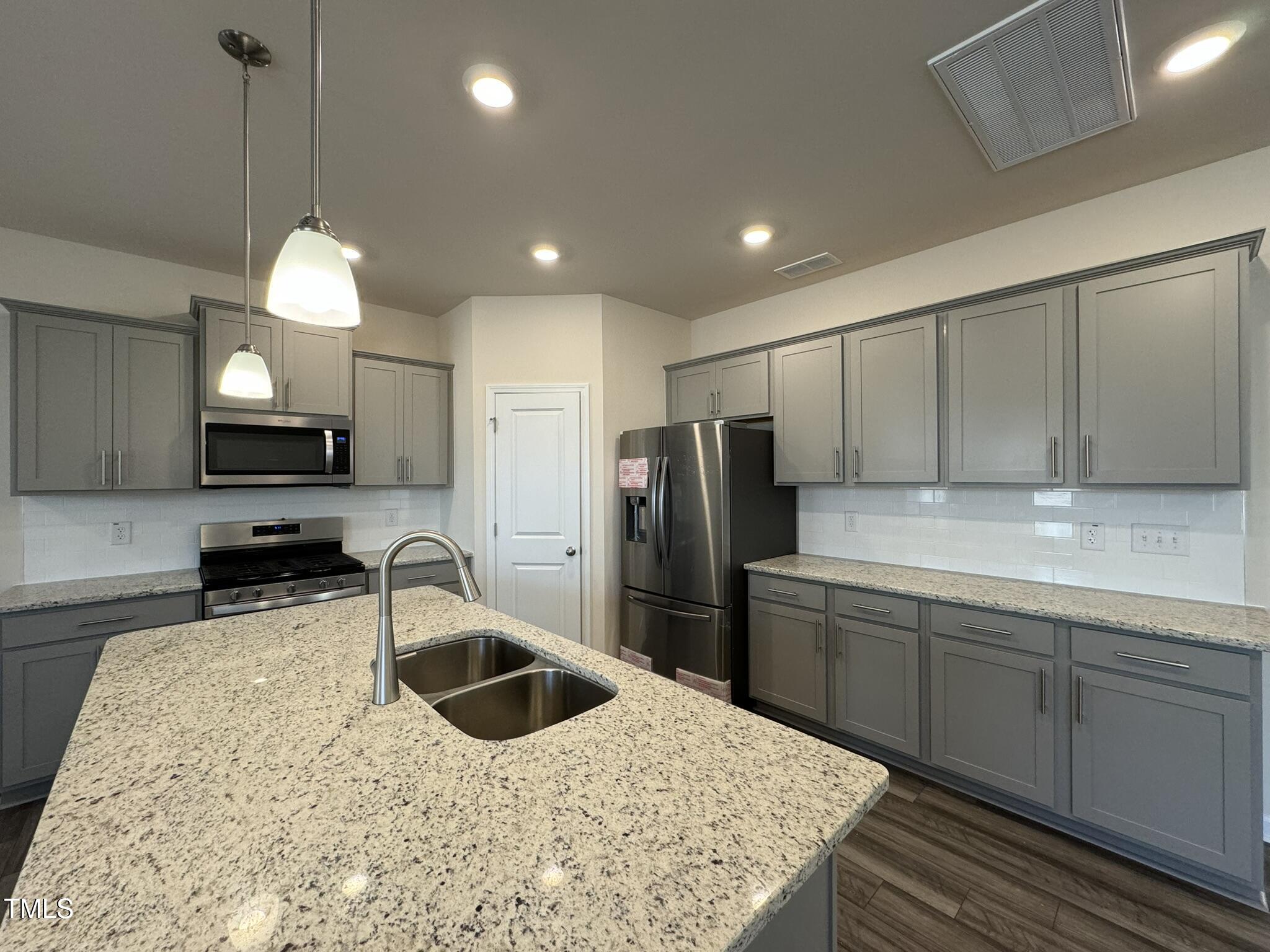 128 Katrine Way Raleigh, NC 27603 - Photo 5 of 34 a kitchen with stainless steel appliances granite countertop a sink refrigerator and cabinets