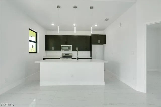 a living room with stainless steel appliances a couch and a flat screen tv