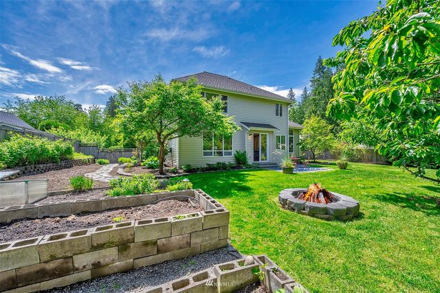 a backyard of a house with table and chairs plants and large tree
