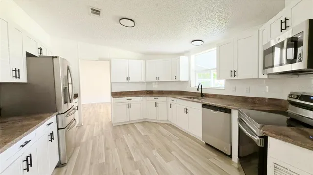 a kitchen with granite countertop a refrigerator stove top oven and sink