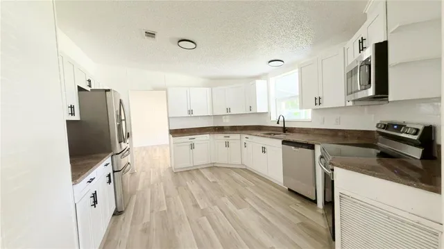 a kitchen with granite countertop a sink appliances cabinets and counter space