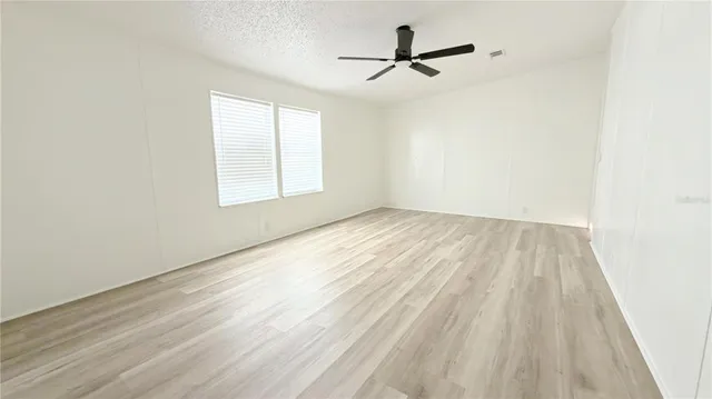 a view of empty room with wooden floor and fan