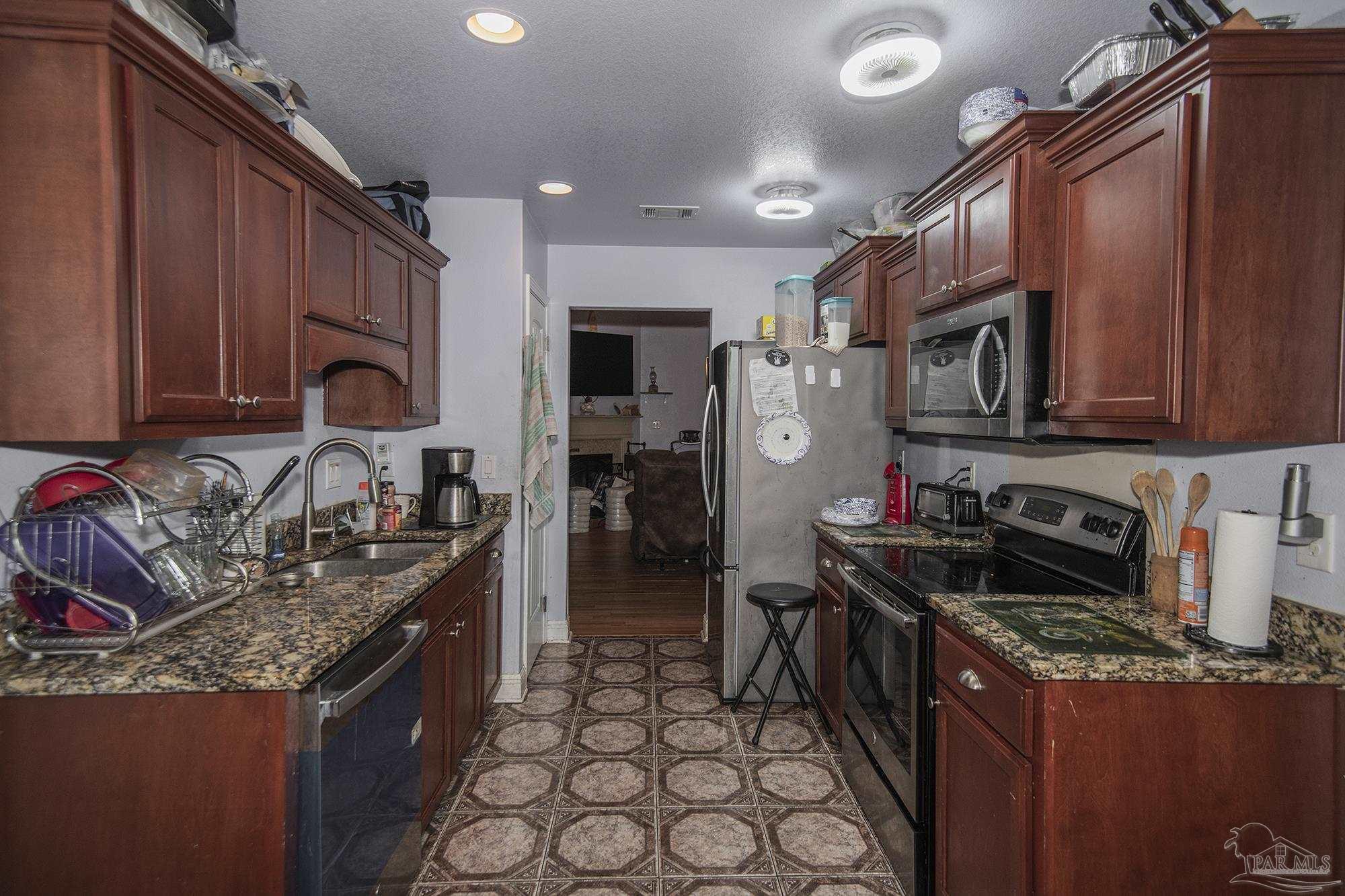 5800 Providence Loop Pensacola, FL 32526 - Photo 7 of 29 a kitchen with granite countertop a stove top oven microwave and cabinets