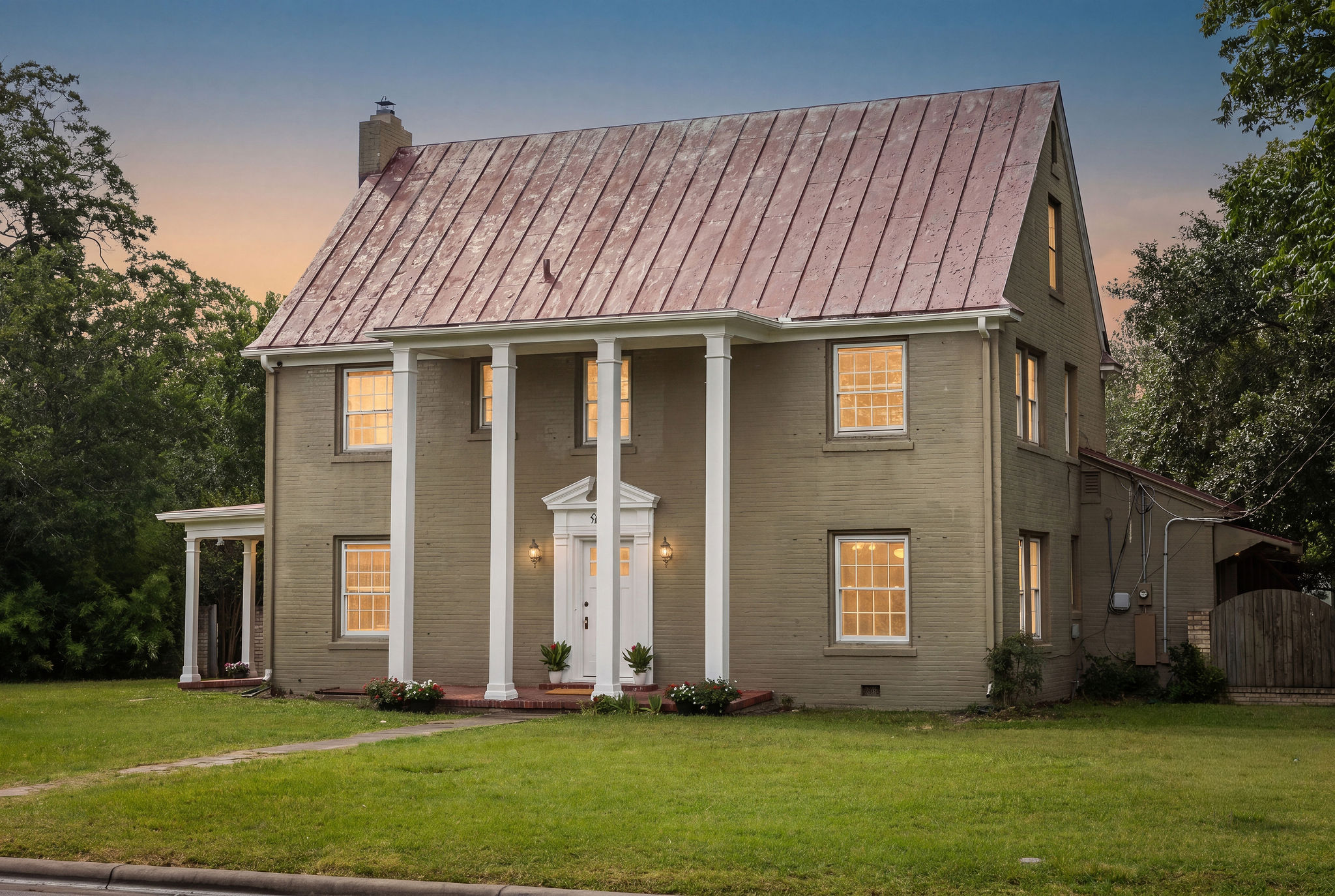 948 Maple Street Lockhart, TX 78644 - Photo 3 of 40 An inviting facade with grand columns and a classic metal roof beckons at twilight.
