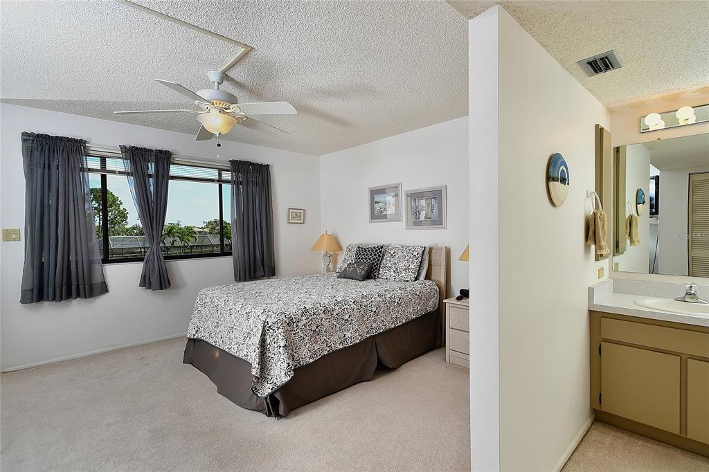 601 Islamorada Boulevard, Unit 24B Punta Gorda, FL 33955 - Photo 19 of 36 a spacious bedroom with a bed a dresser and a chandelier