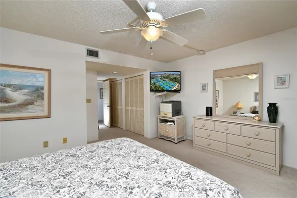 a bedroom with a bed a chandelier and a mirror on dresser