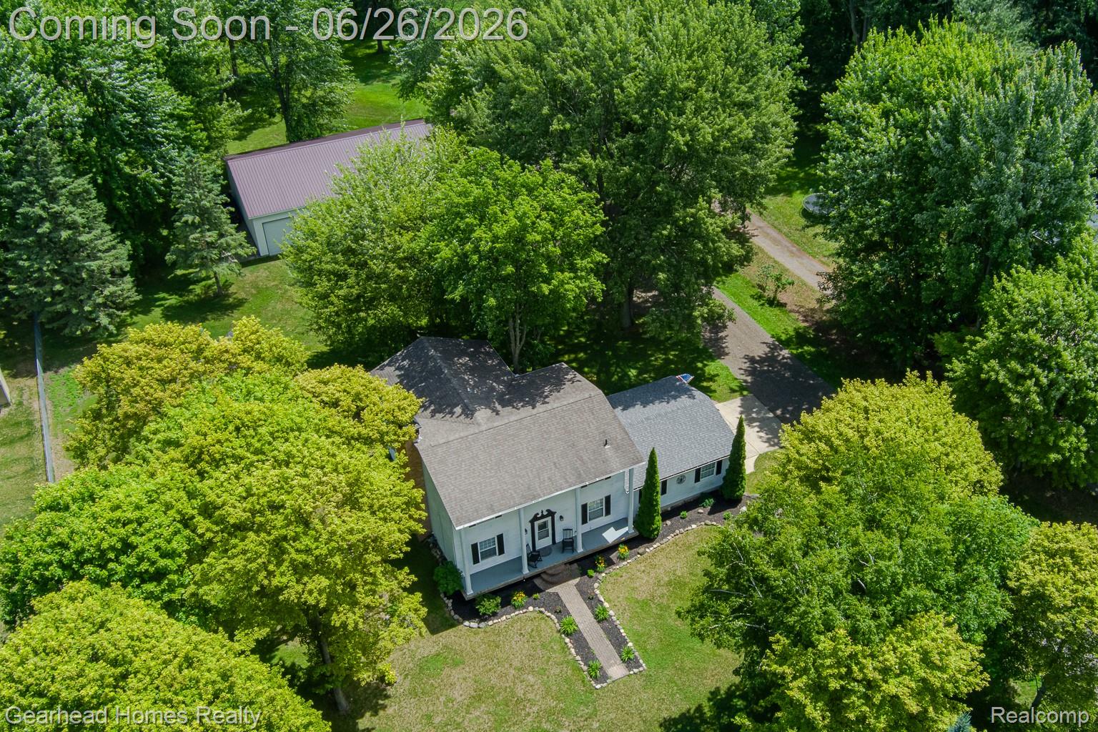 12364 Morrish Road Clio, MI 48420 - Photo 74 of 81 Aerial property view featuring a light-colored residence with a dark roof, surrounded by mature trees