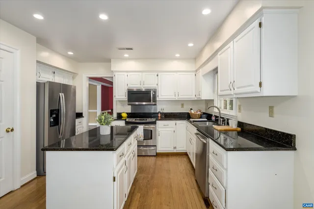 a kitchen with stainless steel appliances granite countertop a refrigerator a stove a sink a microwave and a refrigerator