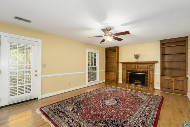 a view of an empty room with a fireplace and wooden floor