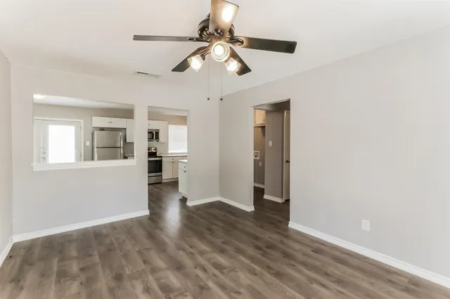 a view of an empty room with wooden floor and a window