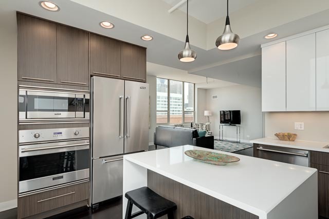 720 West Randolph Street, Unit PH7 Chicago, IL 60661 - Photo 6 of 18 a kitchen with kitchen island a stove a sink and a refrigerator