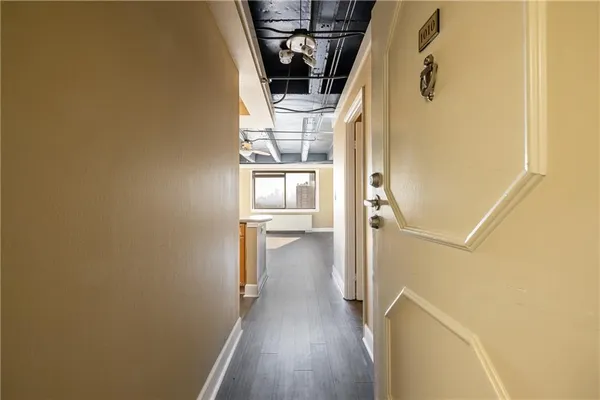 a view of a hallway with wooden floor and a bathroom